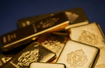 Goldpreis knackt 5000-Dollar-Marke erneut A pile of gold bars sitting on top of a table