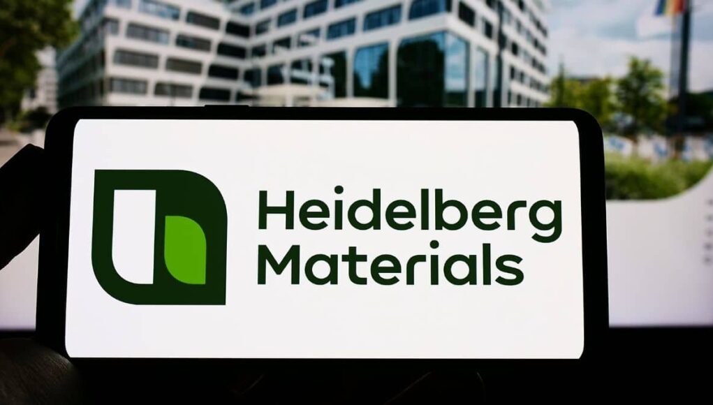 Tablet screen displaying the Heidelberg Materials logo with a green emblem on a white background in an outdoor urban setting.