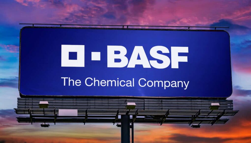 Billboard with the BASF logo and the tagline 'The Chemical Company' against a sunset sky.