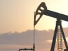 Battalion-Aktie: Handelt es sich hier um ein solides Investment? Two oil pumpjacks silhouetted against a warm sunset sky in an oil field at dusk.