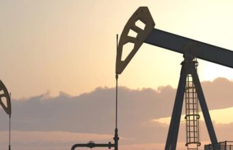 Battalion-Aktie: Handelt es sich hier um ein solides Investment? Two oil pumpjacks silhouetted against a warm sunset sky in an oil field at dusk.