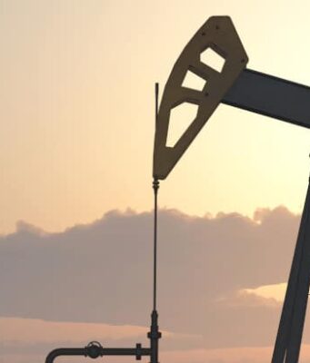 Battalion-Aktie: Handelt es sich hier um ein solides Investment? Two oil pumpjacks silhouetted against a warm sunset sky in an oil field at dusk.