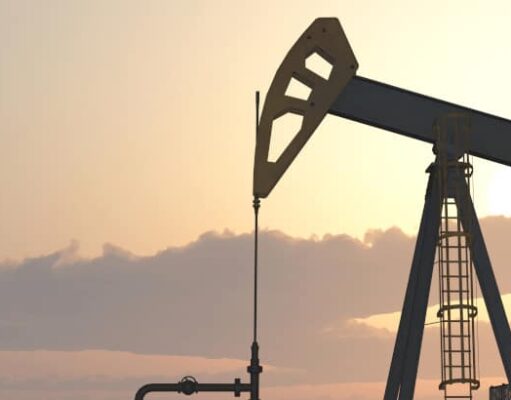 Battalion-Aktie: Handelt es sich hier um ein solides Investment? Two oil pumpjacks silhouetted against a warm sunset sky in an oil field at dusk.