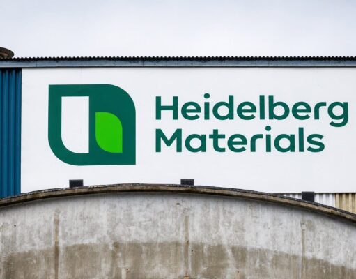 Heidelberg Materials-Aktie -14% im Juniverlauf Large Heidelberg Materials sign with green logo on a white panel against a blue industrial building exterior.