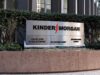 Kinder Morgan-Aktie: Gewinn und Dividende hoch Exterior sign reading KINDER MORGAN with a red lightning bolt logo, set in front of hedges and a stone planter in a business district.