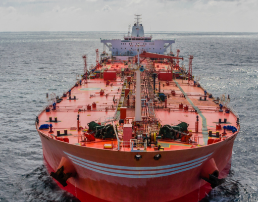 Neue Iran-Eskalation: Beginnt jetzt die zweite Ölpreis-Welle? Front view of a large red oil tanker sailing in calm blue sea, deck filled with equipment and cranes.