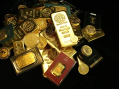 Cambria Gold Mines-Aktie: 4 Aspekte für den Erfolg Pile of gold bars and coins on a dark background, with a prominent 1 kilo gold bar stamped 999.9 fine gold.
