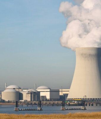 Cameco-Aktie: Diese Milliarden-Chance wird gerade unterschätzt Two large cooling towers emit white steam at a nuclear power plant beside a waterway, with smaller buildings nearby.