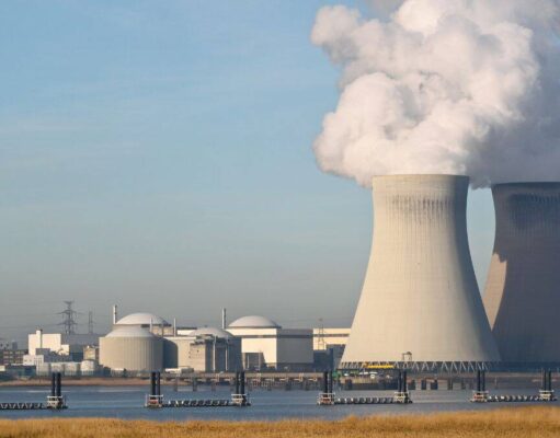Cameco-Aktie: Diese Milliarden-Chance wird gerade unterschätzt Two large cooling towers emit white steam at a nuclear power plant beside a waterway, with smaller buildings nearby.