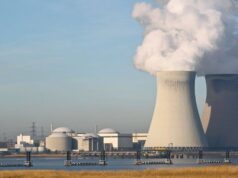 Cameco-Aktie: Zahlen enttäuschen – ist der Boden nah? Two large hyperbolic cooling towers at an industrial power plant emit steam into the sky, with additional buildings and water in the foreground.