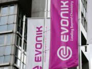 Evonik-Aktie: Ist die Sonderkonjunktur nachhaltig? White and magenta banners on a modern building, displaying the Evonik logo and the slogan 'Leading Beyond Chemistry'.