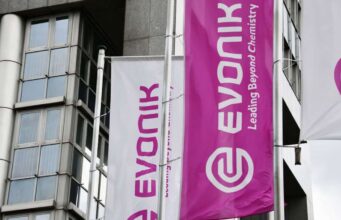 Evonik-Aktie: Ist die Sonderkonjunktur nachhaltig? White and magenta banners on a modern building, displaying the Evonik logo and the slogan 'Leading Beyond Chemistry'.