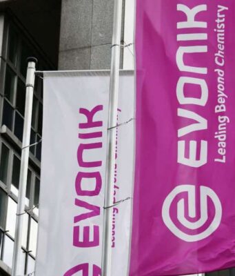 Evonik-Aktie: Ist die Sonderkonjunktur nachhaltig? White and magenta banners on a modern building, displaying the Evonik logo and the slogan 'Leading Beyond Chemistry'.
