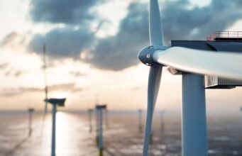 RWE-Aktie: Kursdynamik geht zurück – was ist jetzt ratsam? Offshore wind turbine at sunset with calm sea and distant turbines in the background.