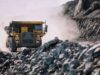 Rio Tinto-Aktie & der Kupferpreis in luftigen Höhen Yellow mining dump truck drives through a dusty rocky quarry with steep rock faces on either side