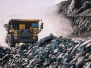 Rio Tinto-Aktie & der Kupferpreis in luftigen Höhen Yellow mining dump truck drives through a dusty rocky quarry with steep rock faces on either side