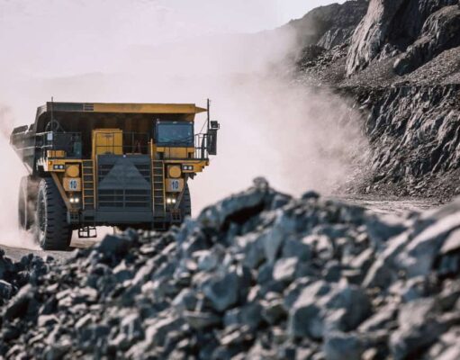 Rio Tinto-Aktie & der Kupferpreis in luftigen Höhen Yellow mining dump truck drives through a dusty rocky quarry with steep rock faces on either side