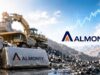 Almonty-Aktie: Droht jetzt die nächste Korrektur? Almonty logo on a rocky mining site with a large excavator and piles of ore under a blue sky