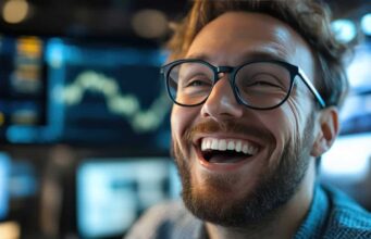 Energy Transfer-Aktie +30% und Dividende: Unser Top-Tipp entwickelt sich prächtig Close-up of a smiling man with a beard and black-rimmed glasses in a high-tech workspace.