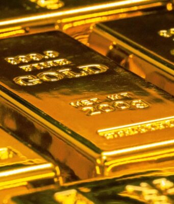Goldpreis unter Druck: Ist die Rallye jetzt in Gefahr? Shiny gold bars stacked together, reflecting light in a secure vault setting (pile of bullion).