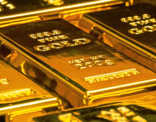 Goldpreis unter Druck: Ist die Rallye jetzt in Gefahr? Shiny gold bars stacked together, reflecting light in a secure vault setting (pile of bullion).