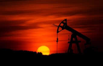Obsidian Energy: Erdöl-Aktie mit Kurspotenzial Silhouette of an oil pumpjack against a red-orange sunset horizon.