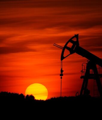 Obsidian Energy: Erdöl-Aktie mit Kurspotenzial Silhouette of an oil pumpjack against a red-orange sunset horizon.