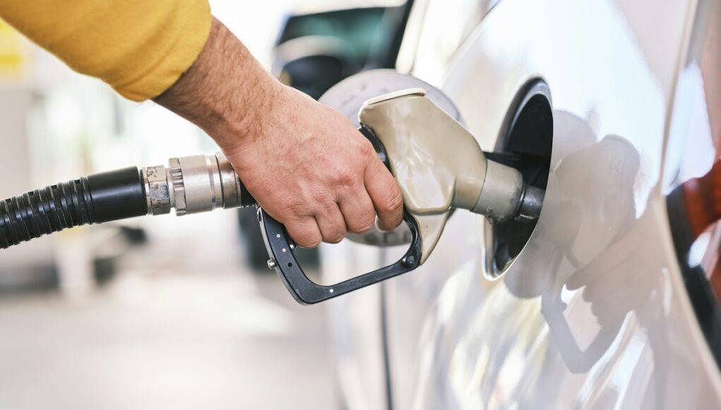 a man pumping gas into his car at a gas station