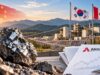 Almonty-Aktie: Ein riesiges Luftschloss? Mining site at sunset with a shiny rock in the foreground, three flags (China, South Korea, Canada) and Almonty Industries documents on a desk in view.