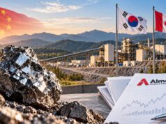 Almonty-Aktie: Ein riesiges Luftschloss? Mining site at sunset with a shiny rock in the foreground, three flags (China, South Korea, Canada) and Almonty Industries documents on a desk in view.