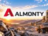 Almonty-Aktie mit -44% – lohnt sich jetzt der Einstieg? Almonty logo over a rock mining site with dump trucks and conveyor belts at sunrise/sunset.