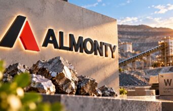 Almonty-Aktie mit -51% – weitet sich die Korrektur aus? Almonty sign on a stone wall with rock piles and a tungsten tile nearby at a mining site during sunset.