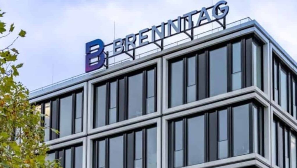 Modern glass office building with a blue-purple 'BRENNITAG' sign on the roof.
