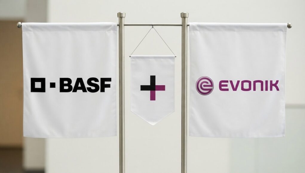 Three white banners on a metal stand showing BASE on the left, a central banner with a black plus and purple vertical bar, and the EVONIK logo on the right.
