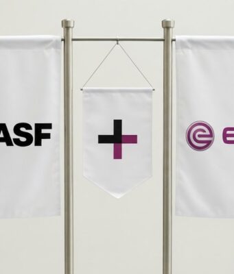 Evonik-Aktie: Kommt jetzt doch eine schnelle Übernahme? Three white banners on a metal stand showing BASE on the left, a central banner with a black plus and purple vertical bar, and the EVONIK logo on the right.