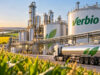Verbio-Aktie: Sind Kurse von 40 € wieder realistisch? Biofuel plant with large white storage tanks labeled 'verbio' and a reflective tanker truck in foreground at sunset, with fields nearby.