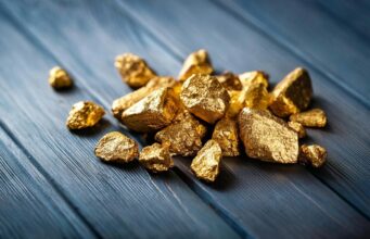 Goldminen-Aktien: 17,4 % Gewinn trotz Gold-Crash – jetzt einsteigen? A pile of gold nuggets sitting on top of a wooden table
