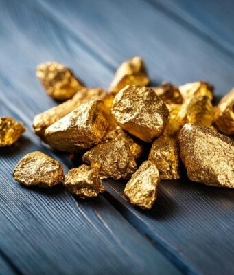 Goldminen-Aktien: 17,4 % Gewinn trotz Gold-Crash – jetzt einsteigen? A pile of gold nuggets sitting on top of a wooden table